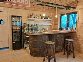 Un rústico espacio de bar con paredes de madera, una vitrina de vidrio y taburetes.