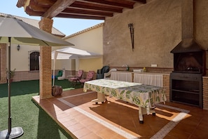 An outdoor patio with a table, chairs, and a brick oven.