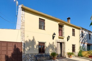 A two-story building with a stone facade, multiple windows, and a small entrance.
