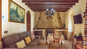 A cozy living room with a sofa, a fireplace, a dining table, and a TV. - Santa Fe Rural Tourist Home with Private Pool, Wi-Fi & Air Conditioning (Montilla)