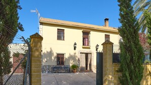 A yellow building with a tiled roof, a stone entrance, a metal gate, and a bench outside. - Santa Fe Rural Tourist Home with Private Pool, Wi-Fi & Air Conditioning (Montilla)