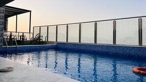 En pool med kristallklart blått vatten, ett glasräcke och några solstolar.