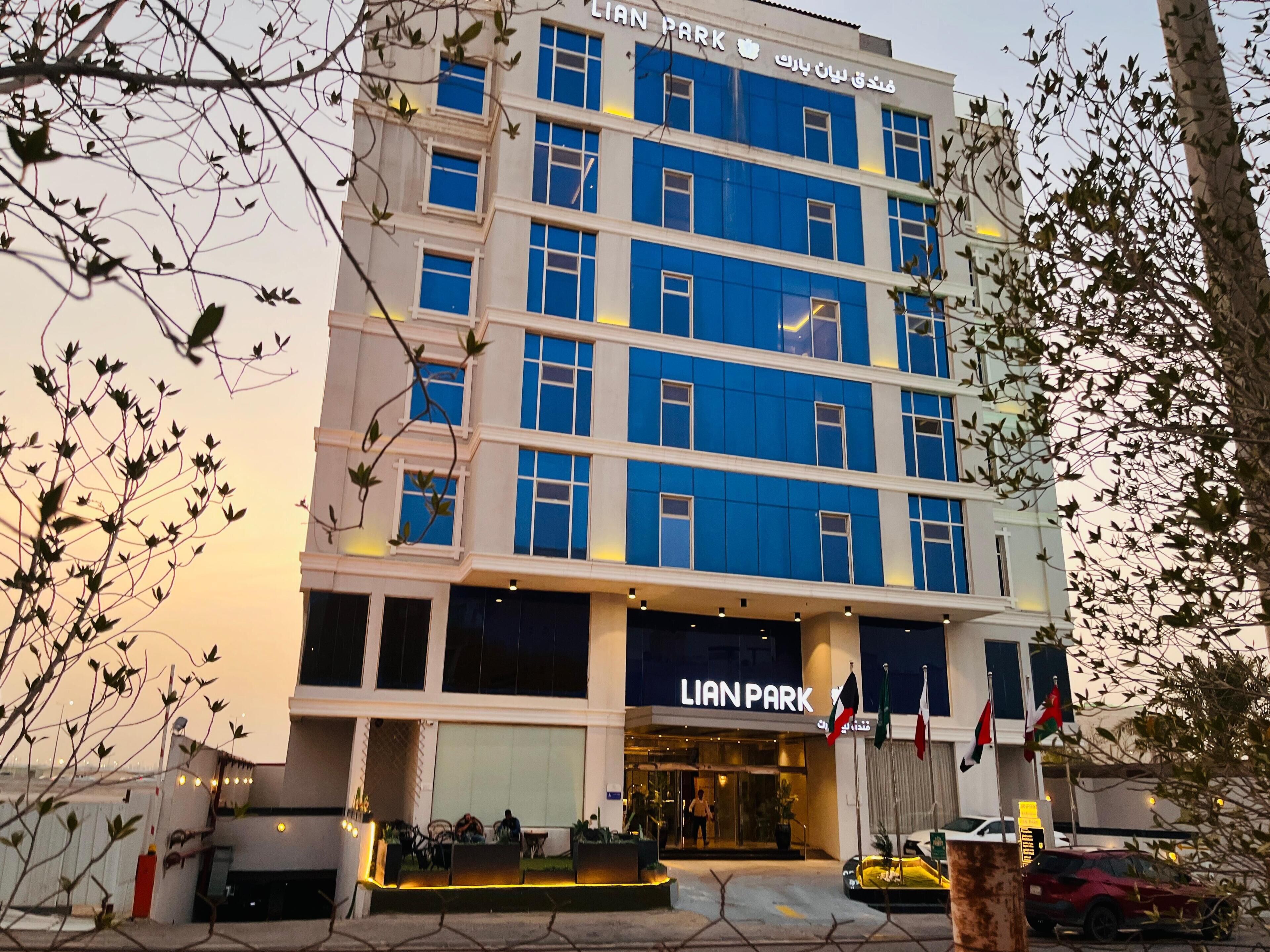 A multi-story hotel with a prominent 'LIAN PARK' sign, outdoor seating area, and multiple flags.