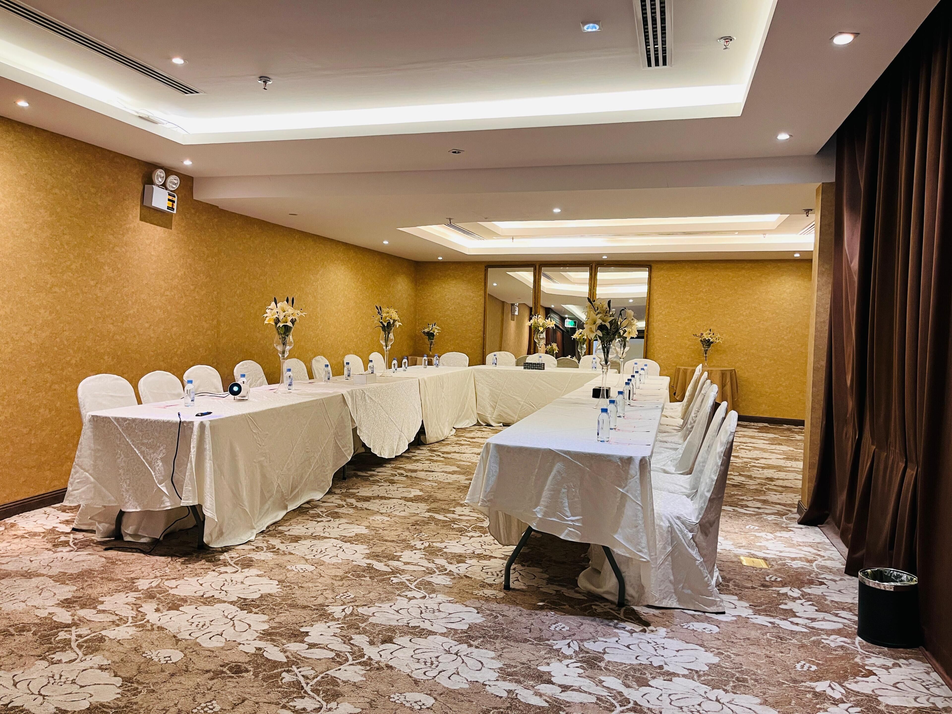 A conference room with tables, chairs, and floral centerpieces.