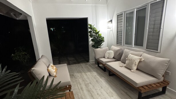 A modern living room with a ceiling fan, a sofa set, a coffee table, and a large window.