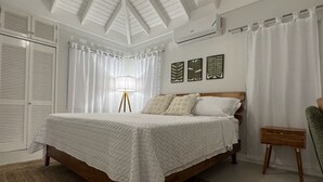 A bedroom with a bed, a ceiling fan, a lamp, and a small table.