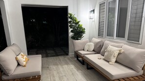 A modern living room with a sofa set, a wooden bench, and a potted plant.