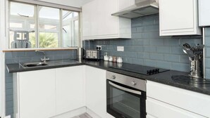 Eine moderne Küche mit weißen Schränken, einer schwarzen Arbeitsplatte und einem Fenster mit Blick auf eine Terrasse.