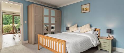 Une chambre à coucher avec un lit en bois, une table de chevet, une armoire et une vue sur l’extérieur.