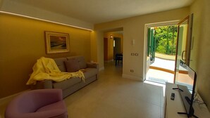 A living room with a sofa, a chair, a TV, and a painting on the wall.