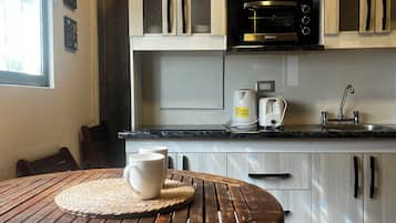 Una cocina con microondas, tostadora y cafetera sobre la encimera.