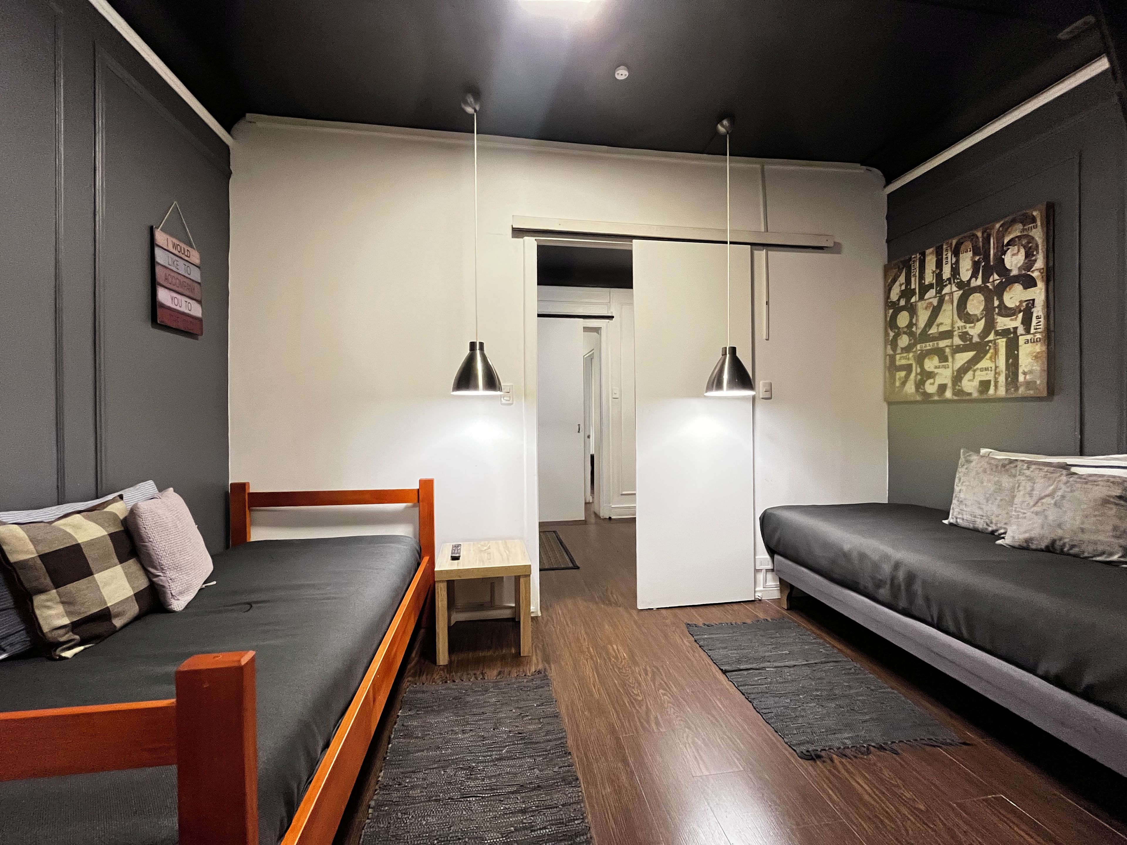 A modern bedroom with a bed, a sofa, a desk, and a hanging light fixture.