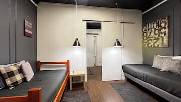 A modern bedroom with a bed, a sofa, a desk, and a hanging light fixture.