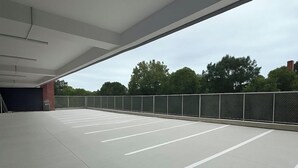 An empty parking lot with marked parking spaces and a metal fence. - LIV Hotel Bronx - Newly Built (Bronx)