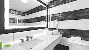 A modern bathroom with a large mirror, a sink, and a toilet.