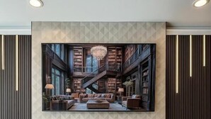 A modern living room with a fireplace, bookshelves, and a chandelier. - LIV Hotel Bronx - Newly Built (Bronx)
