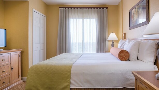 A hotel room with a bed, a television, a desk, and a lamp. - Charming 1-bedroom suite in Exciting Orlando! (Lake Buena Vista)
