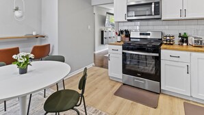 A modern kitchen with white cabinets, stainless steel appliances, and a wooden countertop. - MKE 2 Bed W/ PKNG 15M Downtown (Milwaukee)