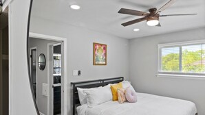 A bedroom with a bed, a ceiling fan, a window, and a door leading to a bathroom. - MKE 2 Bed W/ PKNG 15M Downtown (Milwaukee)