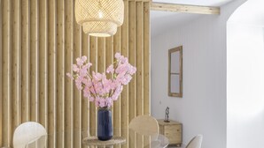 A modern dining area with a glass table, wooden panel wall, and a woven light fixture. - Country House 'El Rincón de Hugo' with Mountain View, Private Terrace, A/C and Wi-Fi (Alcalá De Los Gazules)