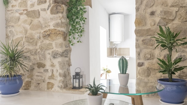 A room with a stone wall, a glass table, and potted plants. - Country House 'El Rincón de Hugo' with Mountain View, Private Terrace, A/C and Wi-Fi (Alcalá De Los Gazules)