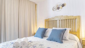 A neatly made bed with a floral-patterned bedspread, two pillows, and rolled towels on the side. - Country House 'El Rincón de Hugo' with Mountain View, Private Terrace, A/C and Wi-Fi (Alcalá De Los Gazules)