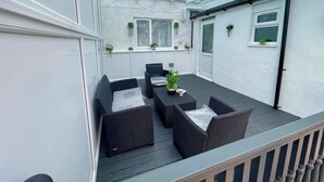 Eine überdachte Terrasse mit Gartenmöbeln und Topfpflanzen.