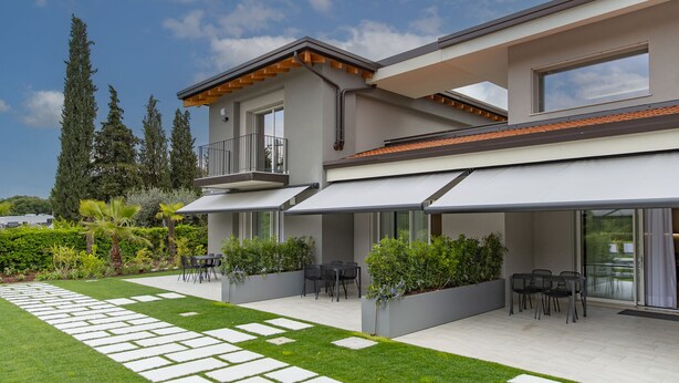 A modern two-story house with a covered patio, outdoor seating, and a well-maintained garden. - Modern apartment with pool a few steps from Lake Garda (Padenghe Sul Garda)