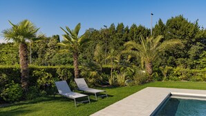 A pool area with two lounge chairs and a well-maintained lawn. - Modern apartment with pool a few steps from Lake Garda (Padenghe Sul Garda)