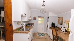 A compact kitchen with white cabinetry, a granite countertop, and a hanging light fixture.