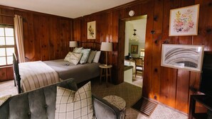 A cozy bedroom with a bed, bedside lamps, a dresser, and a television.