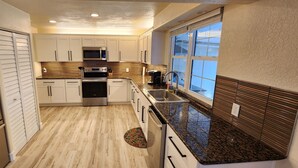 A modern kitchen with white cabinets, stainless steel appliances, and a window providing natural light. - 4-bedroom heated Pool house in lovely Osprey, 5 minutes to the beach (Osprey)