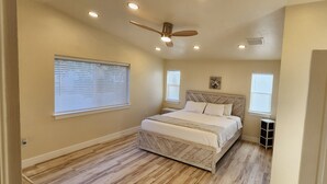 A bedroom with a wooden floor, a bed with white bedding, a ceiling fan, and two windows with blinds. - 4-bedroom heated Pool house in lovely Osprey, 5 minutes to the beach (Osprey)