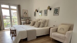 A bedroom with a bed, a chair, a desk, and a large window. - La Millière - "Marie-Anne & Marie-Adélaïde & Charette" - Chambres indépendantes - Piscine & campagne - (Le Poiré-sur-Vie)