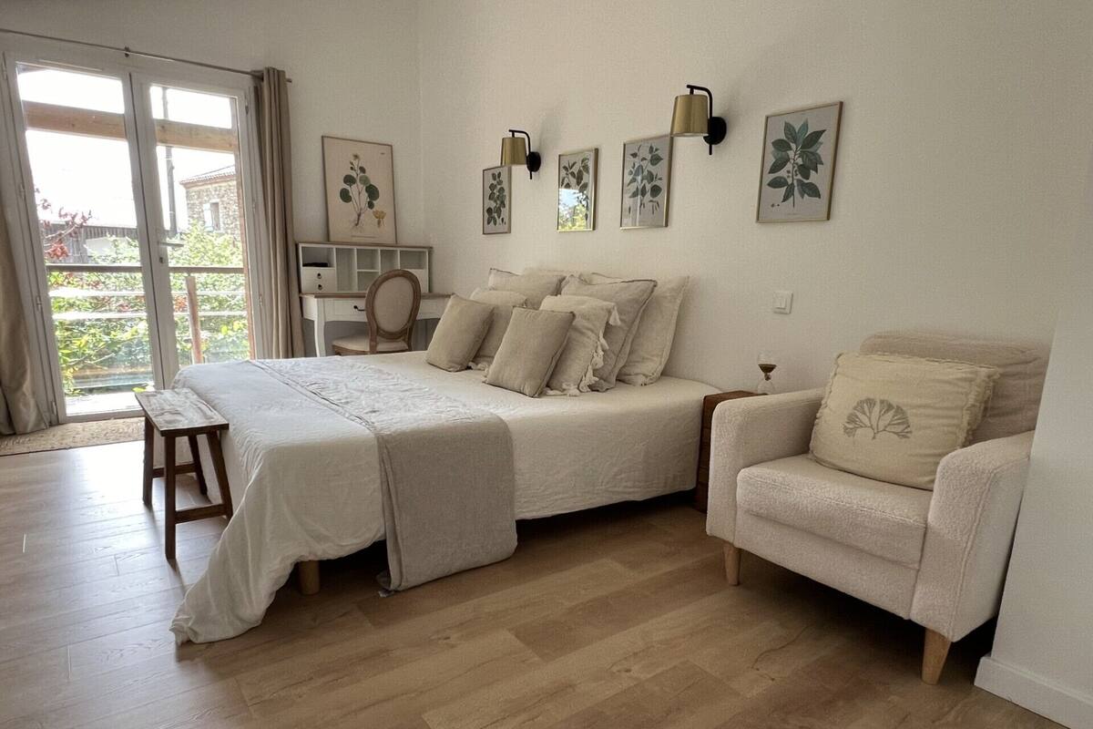 Une chambre à coucher avec un lit, une chaise, un bureau et une grande fenêtre.