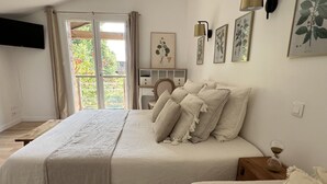 A bedroom with a large bed, a bedside table, a chair, a desk, and a window with curtains. - La Millière - "Marie-Anne & Marie-Adélaïde & Charette" - Chambres indépendantes - Piscine & campagne - (Le Poiré-sur-Vie)