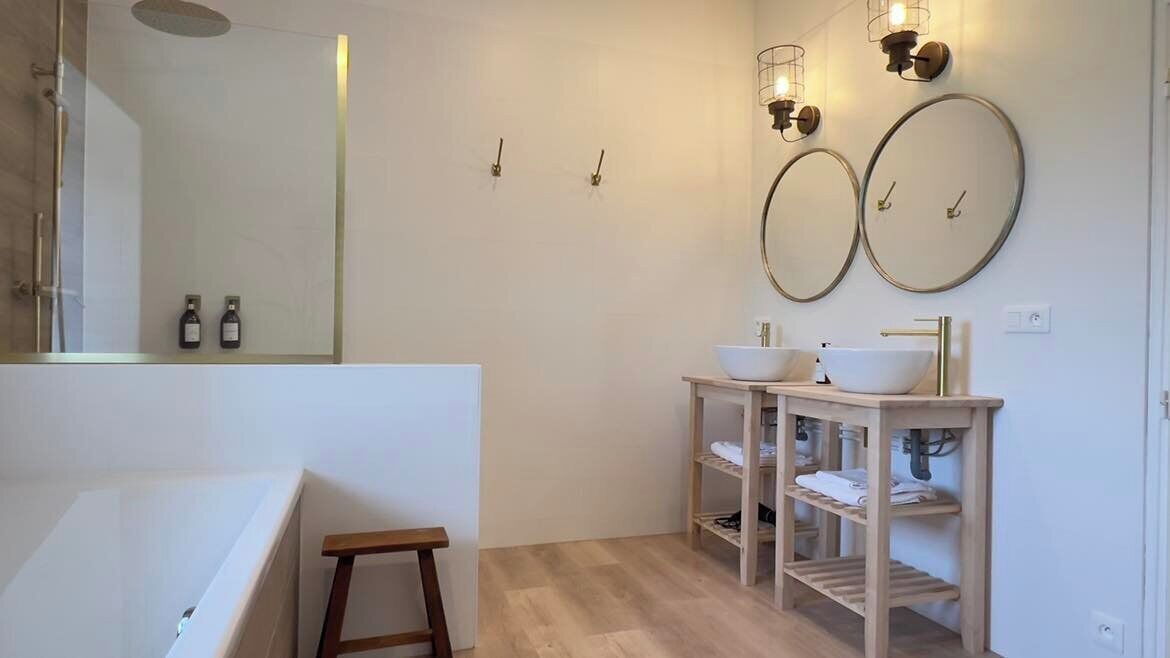 Un baño moderno con bañera, dos lavamanos, tocador con repisas e iluminación empotrada.