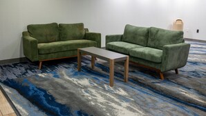 Ein Zimmer mit zwei grünen Sofas, einem kleinen Tisch und einem gemusterten Teppich.
