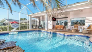 Une piscine entourée de parois en verre, des chaises longues en bois et un panneau indiquant la présence de Netflix.