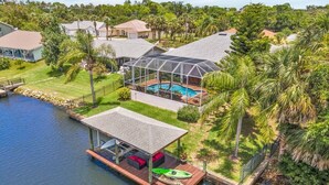 Une maison avec une piscine, un espace extérieur couvert et un quai avec un kayak.