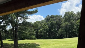 Una terraza de madera con vista a un campo cubierto de hierba y árboles.