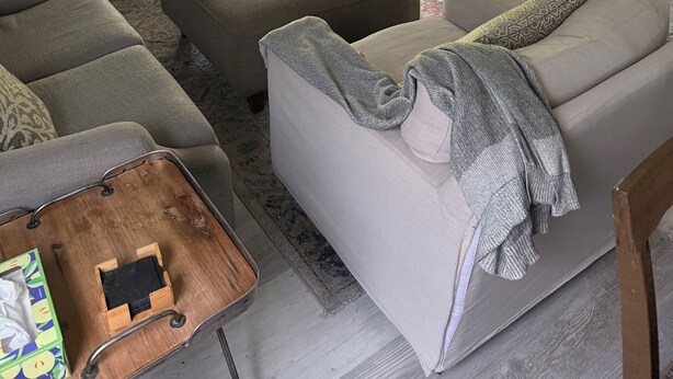 Una sala de estar con sofá modular, reposapiés y mueble para televisor con televisor de pantalla plana.