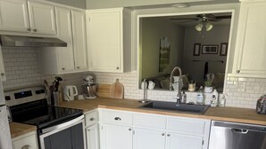 Una cocina moderna con armarios blancos, electrodomésticos de acero inoxidable y encimera de madera.