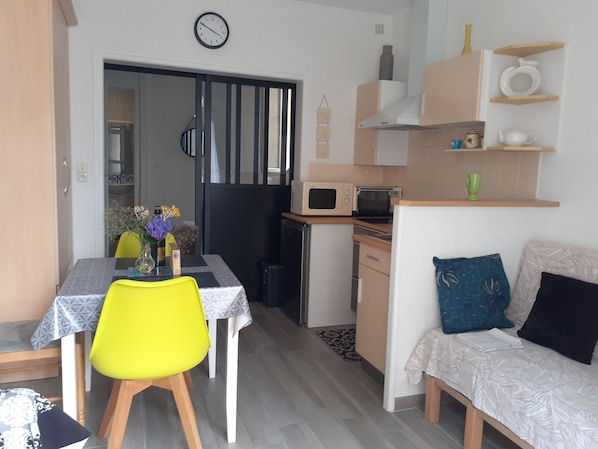 A compact living space with a dining area, kitchenette, and a sofa.