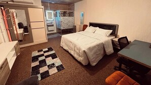 Een slaapkamer met een bed, een bureau, een stoel en een zichtbare badkamer door een open deur.