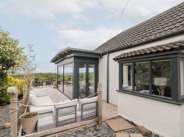 A modern house with a covered patio, a white exterior, and large windows. - Sea Haven (Filey)