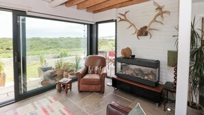 Een moderne woonkamer met een glazen deur naar een balkon, een open haard en decoratie bestaande uit geweien.