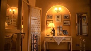 A warmly lit room with a vintage-style lamp, a 'Café' sign, and framed pictures on the wall. - Hostalet dels Indians (Begur)