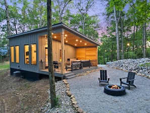 A cabin with a deck, outdoor seating, and a fire pit.