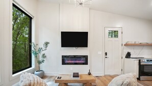 Una sala de estar moderna con chimenea, televisor de pantalla plana, mesa de comedor y sofá.